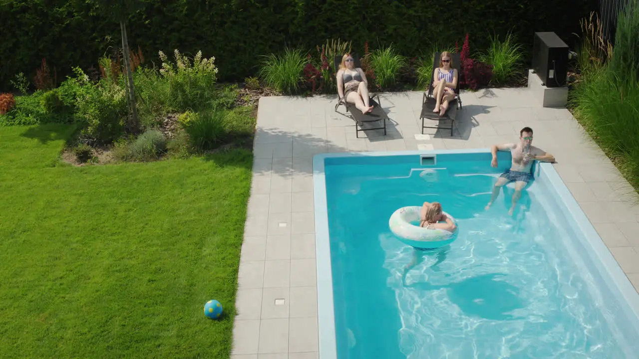 Happy family relaxing by the pool on a hot summer day