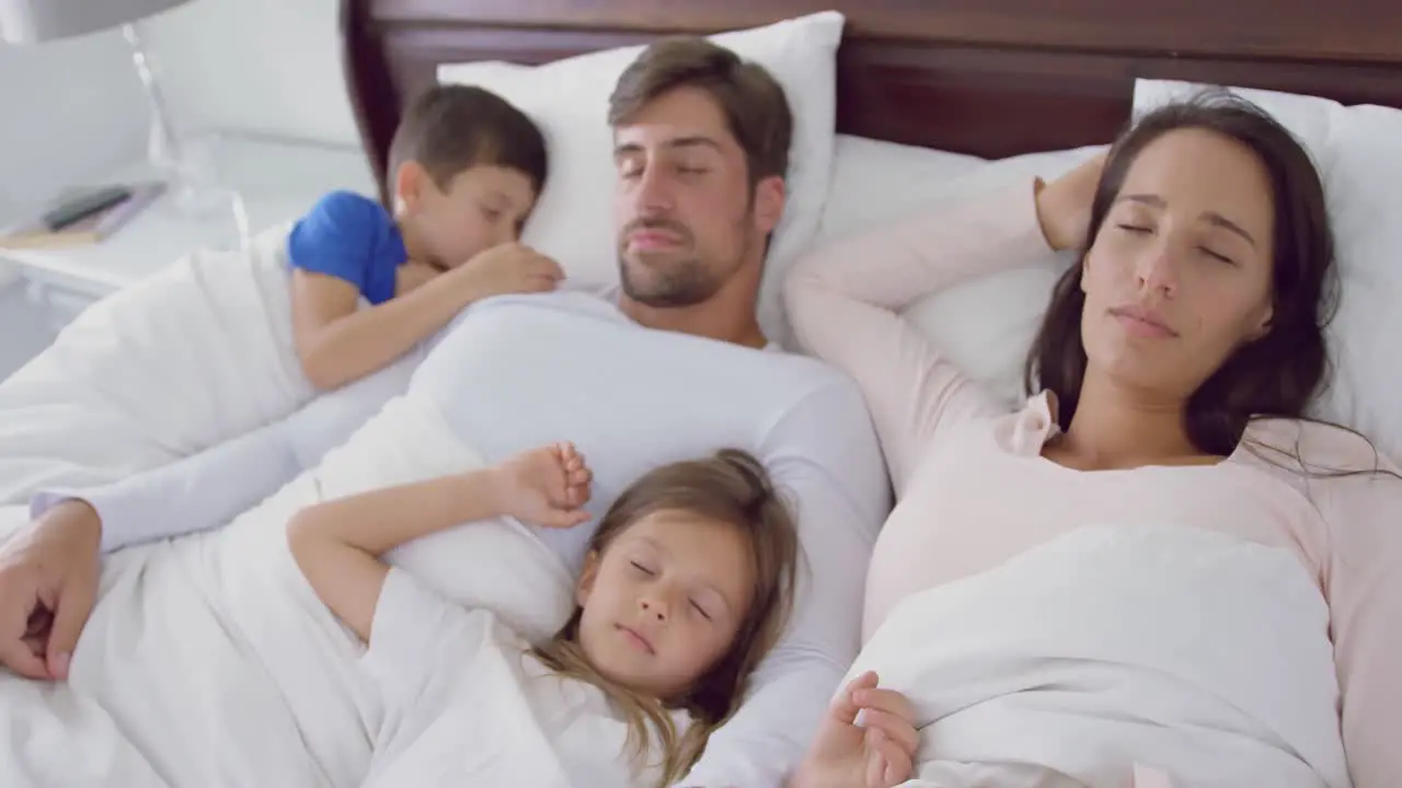 Family sleeping together on bed in bedroom at home 4k