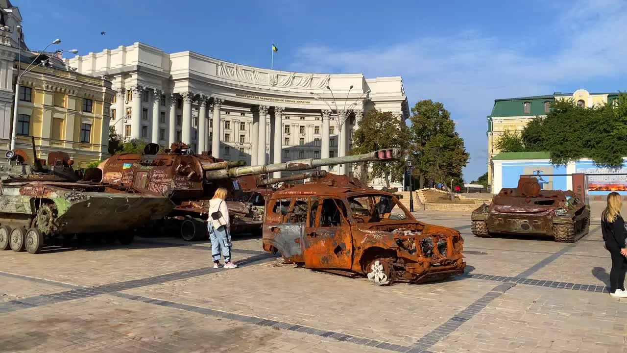 Mykhailivska Square filled with shelled tanks and cars from the Russia Ukraine war in Kyiv city center burned and destroyed war vehicles blue sky on a sunny day 4K shot