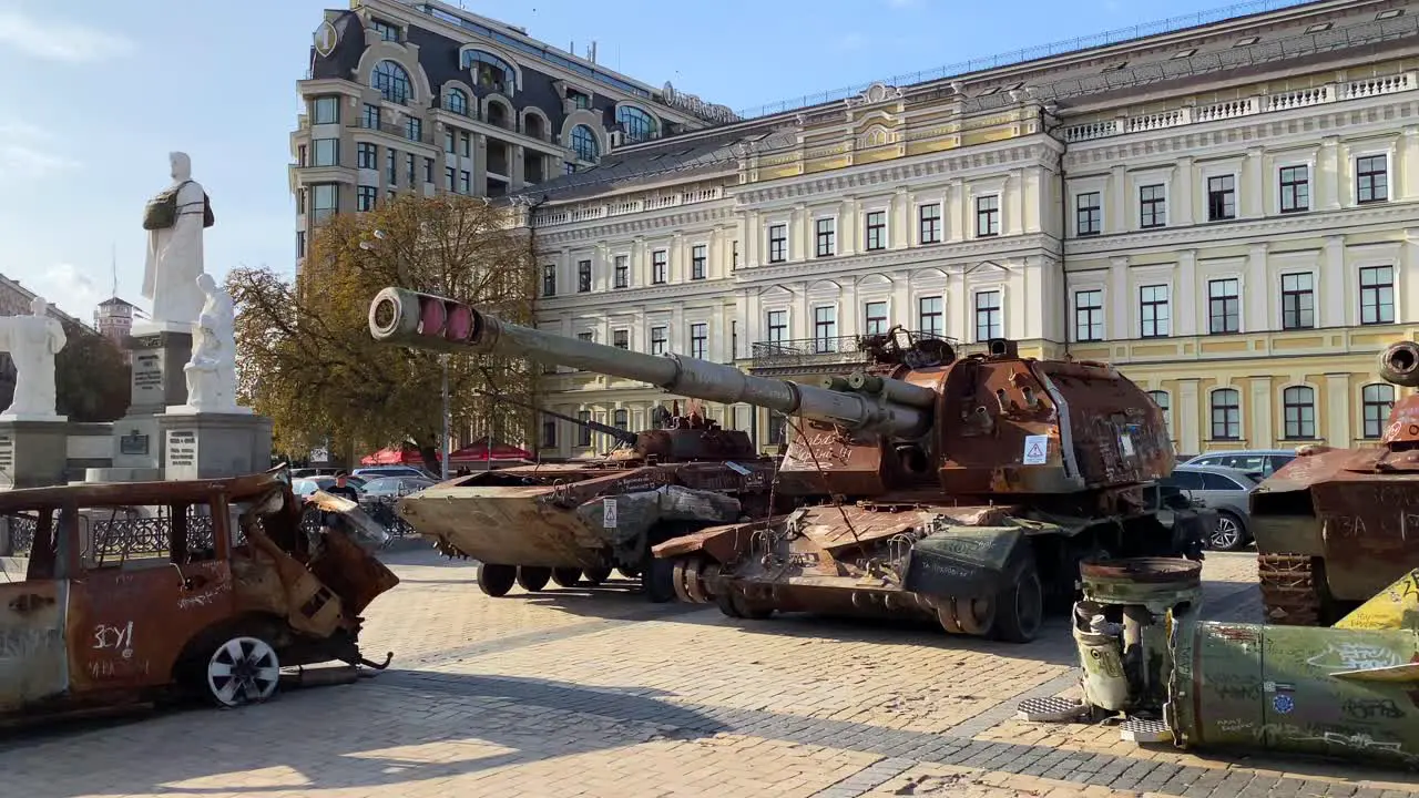 Mykhailivska Square filled with shelled tanks and cars from the Russia Ukraine war in Kyiv city center burned and destroyed war vehicles big missile rocket sunny day 4K shot