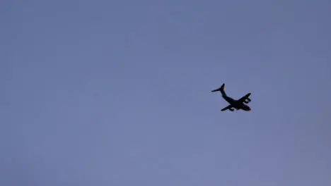 Handheld Shot Looking Up at Military Aircraft Flying at Sunset