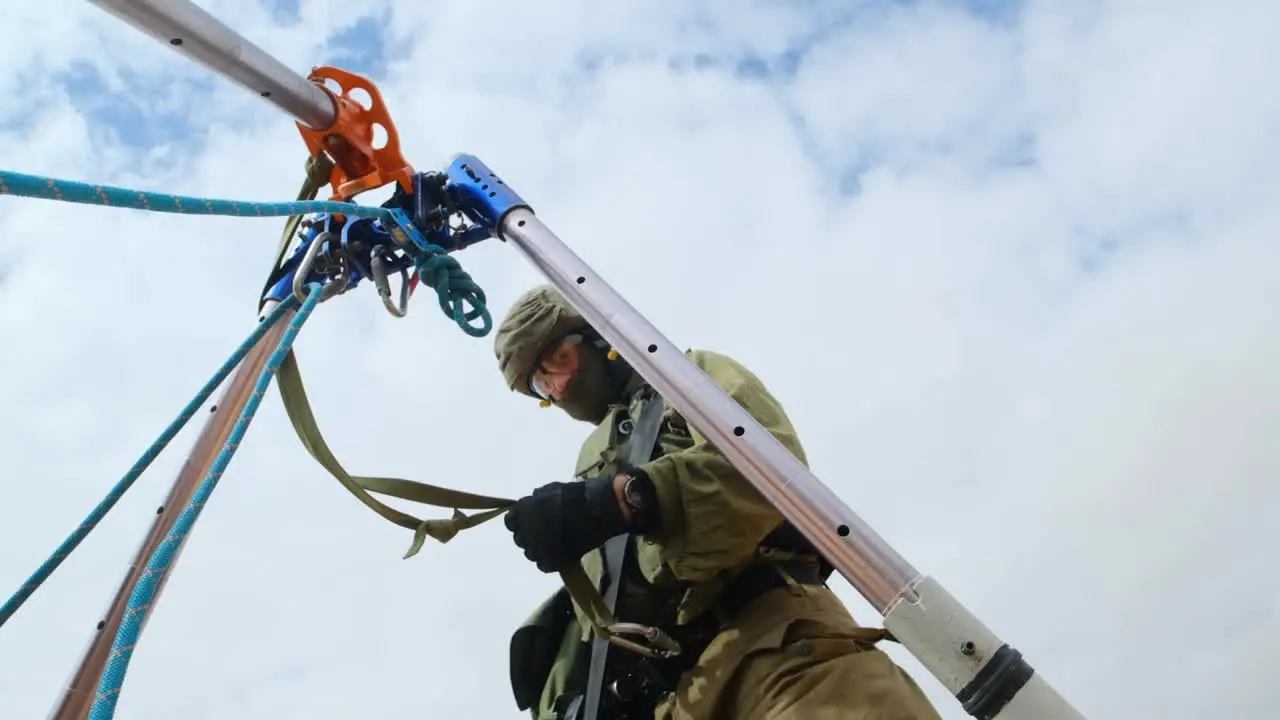 A soldier in a tunnel unit assembles metal rings on a tripod in preparation for continuing professional work