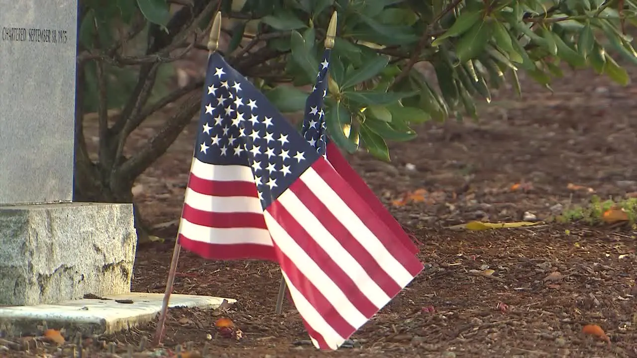 SMALL AMERICAN FLAG BY TOMBSTONE IN CEMETERY