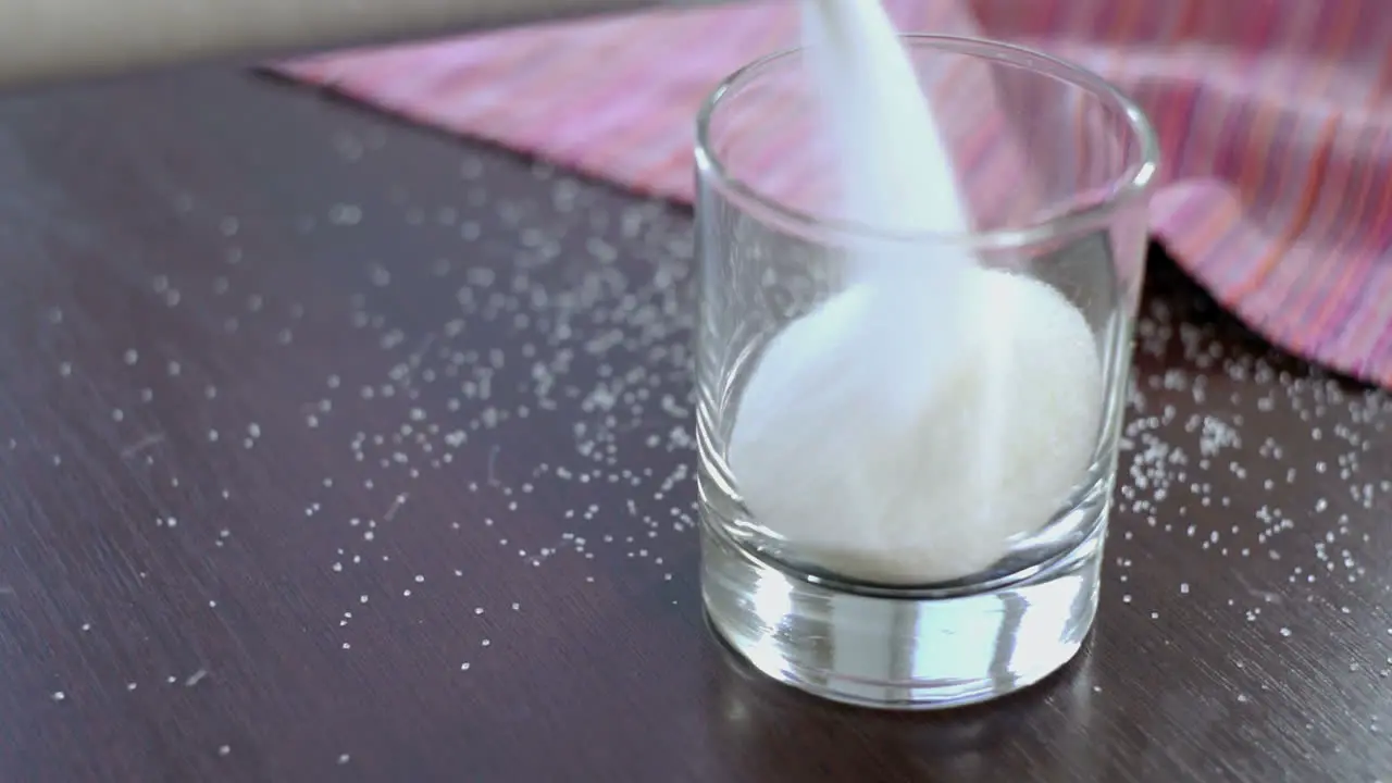 Pouring sugar in glass container prepare for baking Closeup of glass with sugar