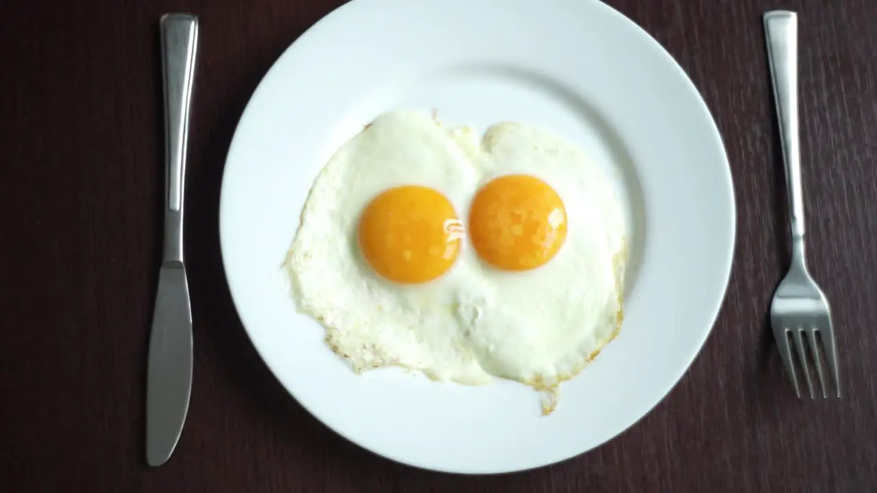 Fried eggs on plate Putting plate with fried eggs on wooden table