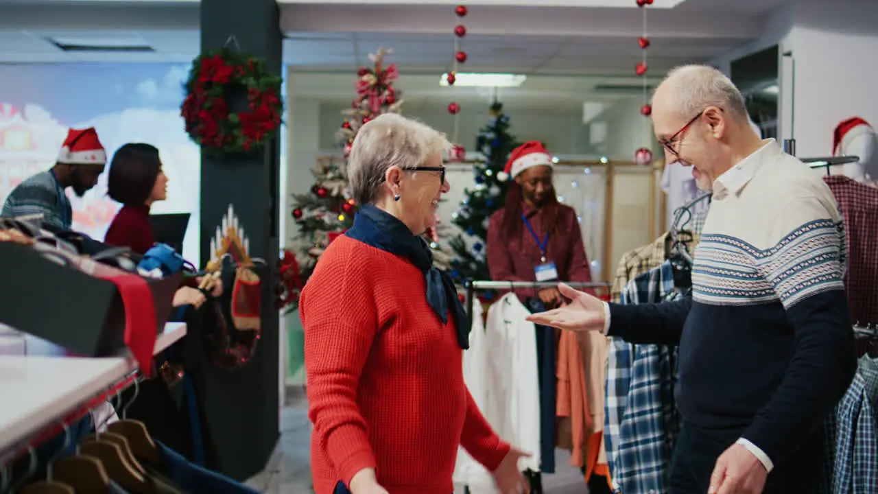 Happy elderly couple dancing around in xmas ornate shopping mall clothing store finally finding perfect gifts for family members at Christmas gathering during winter holiday season