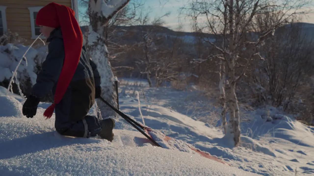 A boy pulling his led up the hill in knee-high snow during Christmas in Norway