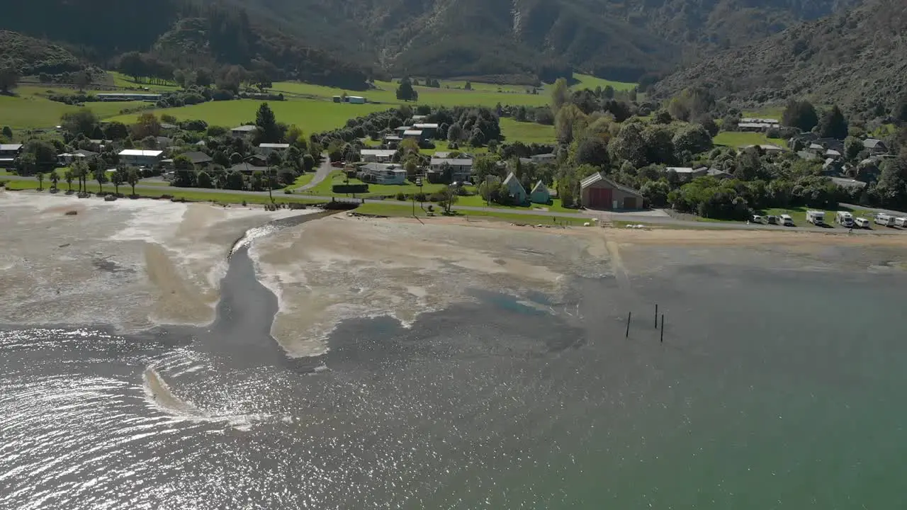 SLOWMO Flying over sea water with Anakiwa town in background Queen Charlotte Sound Marlborough Sounds South Island New Zeland Aerial