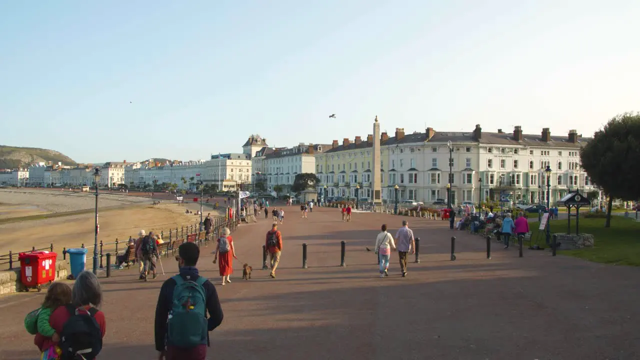 Slow-mo of tourists walking along Llandudno promenade Wales