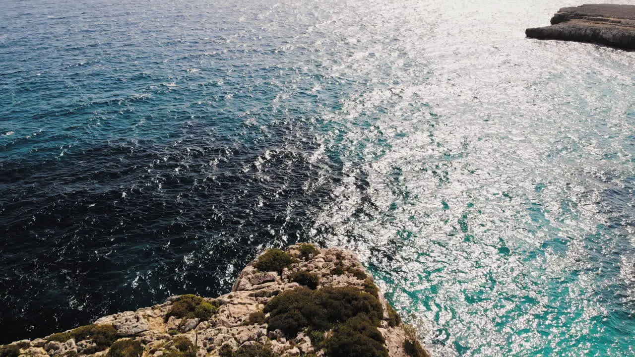 Forward flying drone shot over a sea arch with a tourist walking near Cala Varques in Majorca