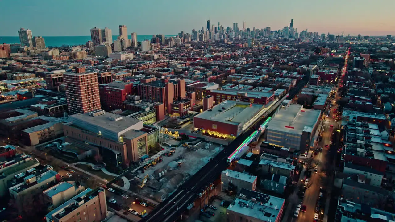 orbiting cta holiday train decorated in chistmas on Brown Lane railroad and tilting up with an epic chicago skyline view at sunset 4k