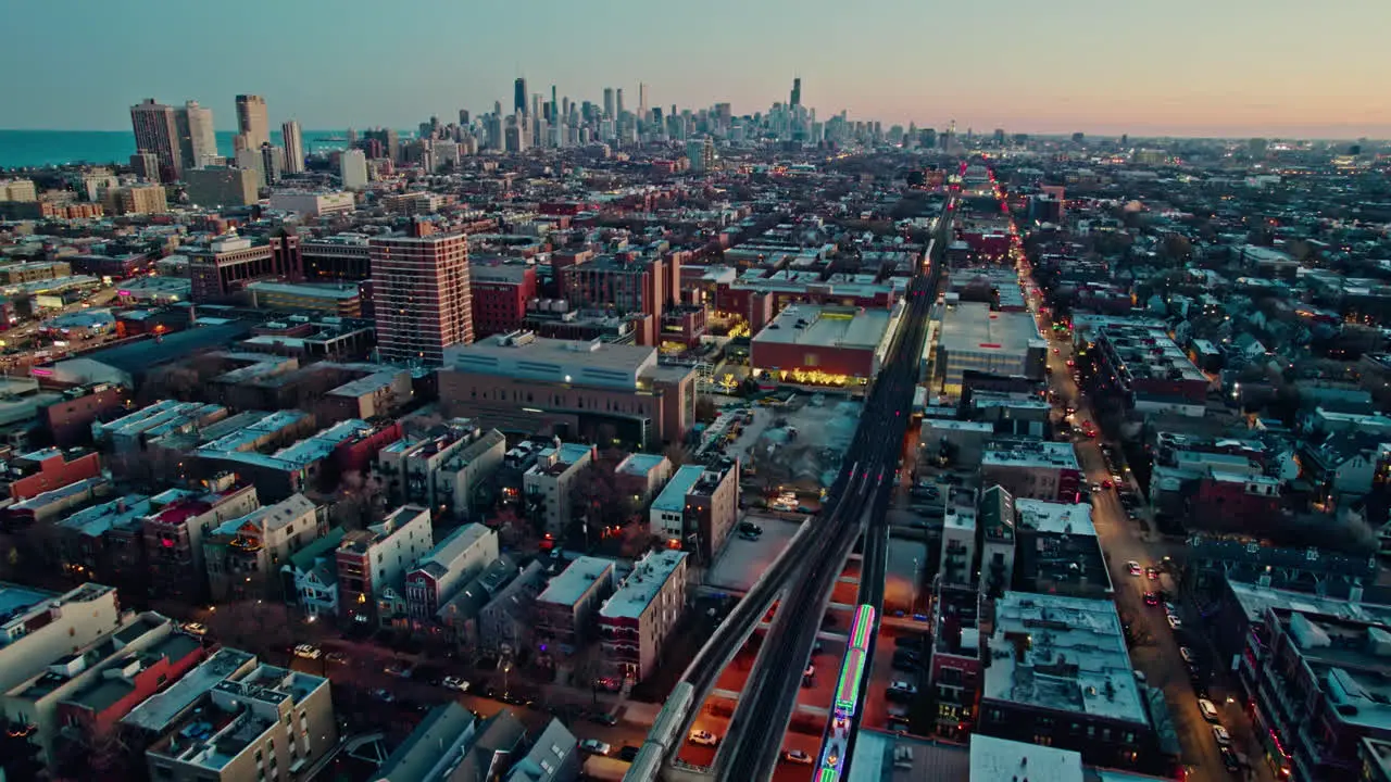 following cta holiday train decorated in chistmas on Brown Lane railroad and tilting up with an epic chicago skyline view at sunset 4k