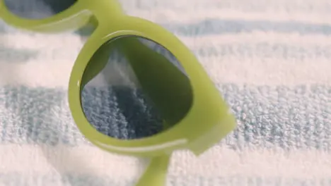 Summer Holiday Concept Of Hand Picking Up Green Sunglasses On Beach Towel