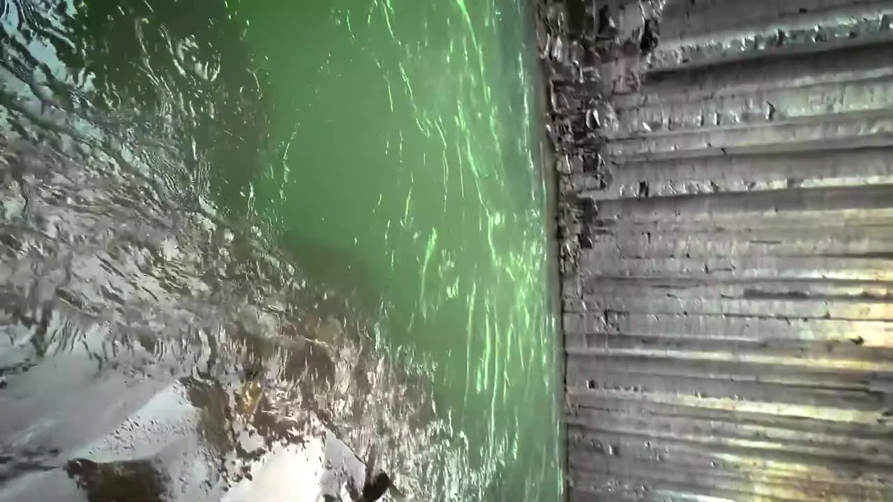 Emerald green water flowing down the Studlagil Canyon in Iceland slow motion panning to the exit and with blue skies