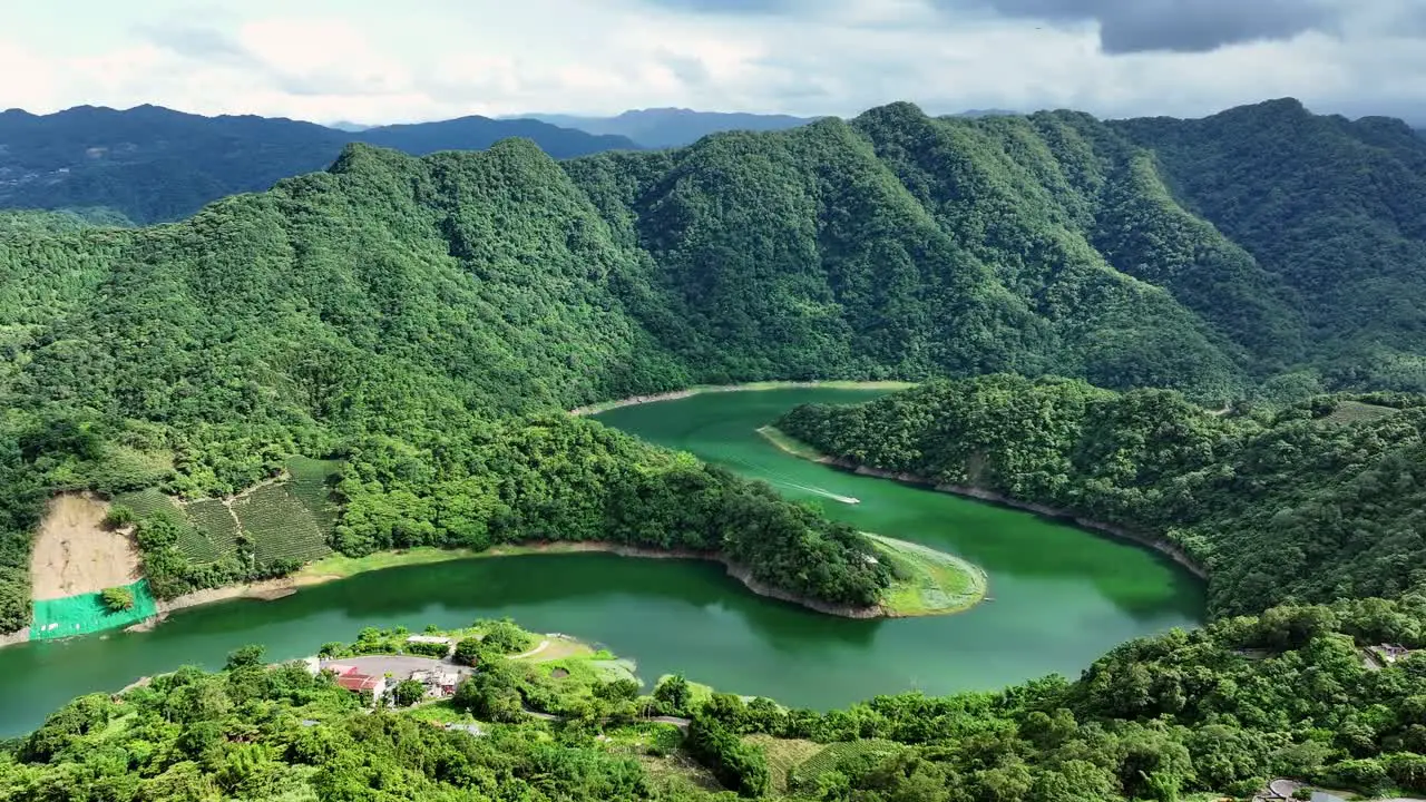 Cinematic drone shot showing idyllic Feitsui Reservoir with green river and overgrown mountains in Taiwan