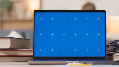 Blue Screen Laptop on Desk At Home With Student Working In Background 1