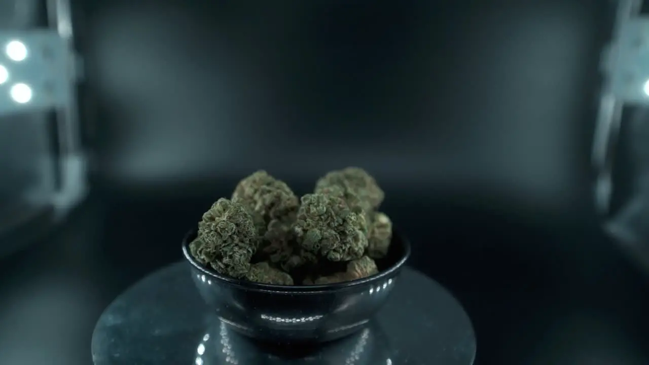 Green Dried Marijuana Buds Close Up Shot pile of dried marijuana plants in a shiny bowl trichomes strains on a reflecting rotating stand studio lights cinematic slow motion 120 fps follow left