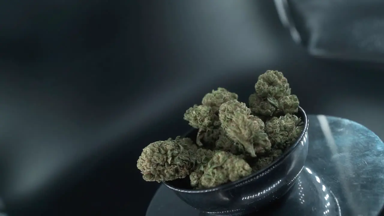 Green Dried Marijuana Buds Close Up Shot pile of dried marijuana plants in a shiny bowl trichomes strains on a reflecting rotating stand studio lights cinematic smooth rotate slow motion 120 fps