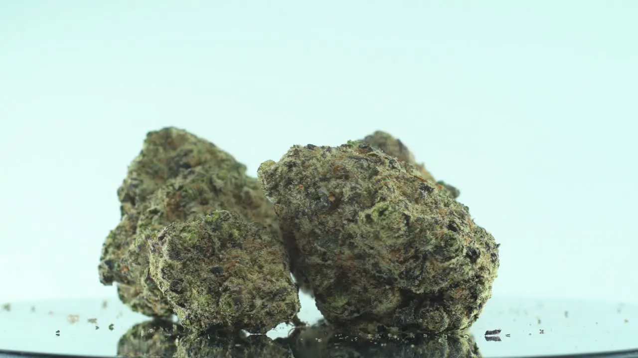 Close up shot of a Marijuana sativa Super Lemon Haze flowers yellow green and purple Kush on a reflecting 360 rotating stand Slow motion 4K video