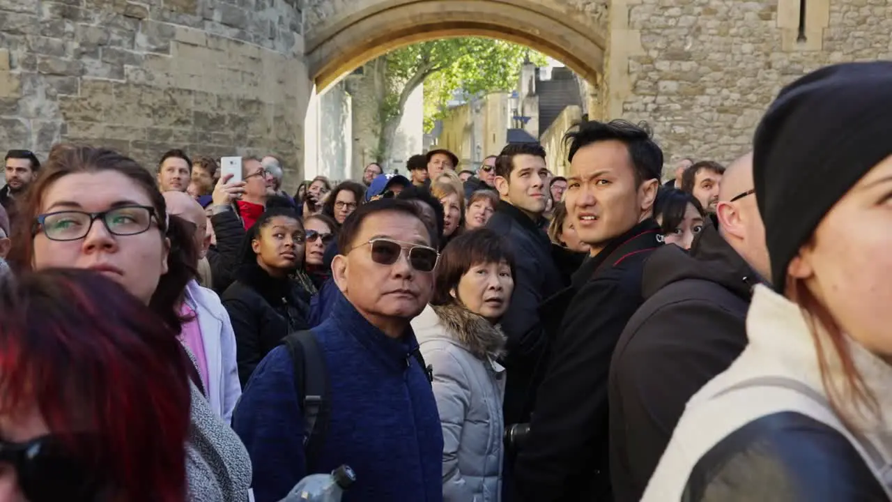 Big group of tourists turn toward the camera and stare amazed during a tour of the Tower of London