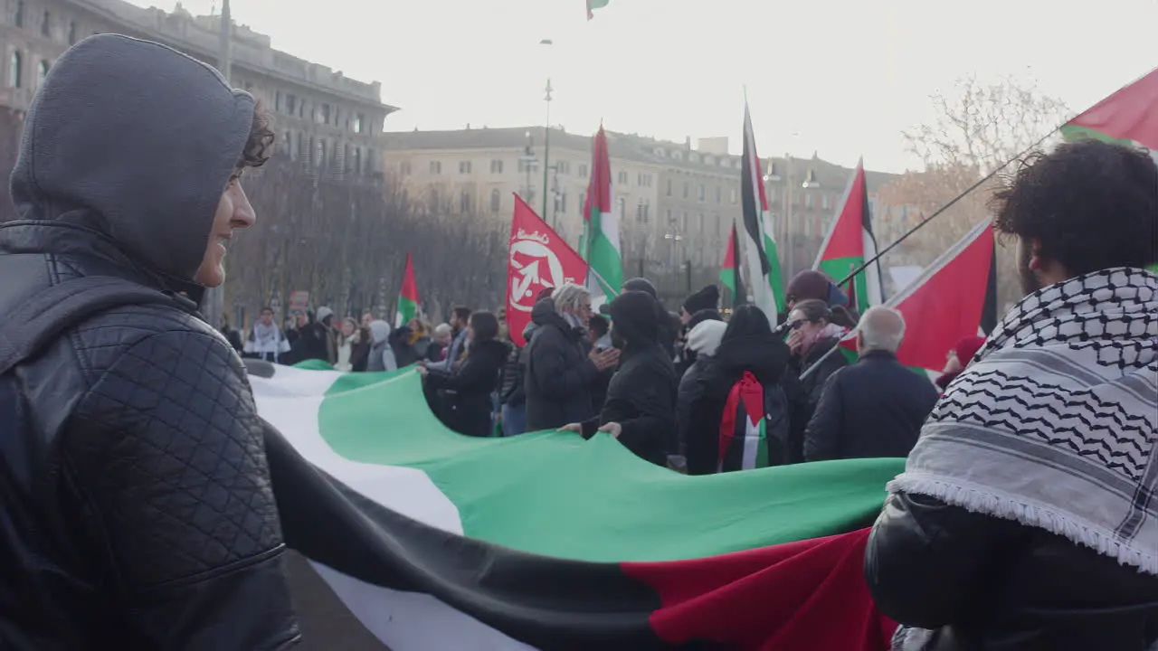 Manifestant stand with flag close to castello sforzesco Milan asking for freeing Palestina