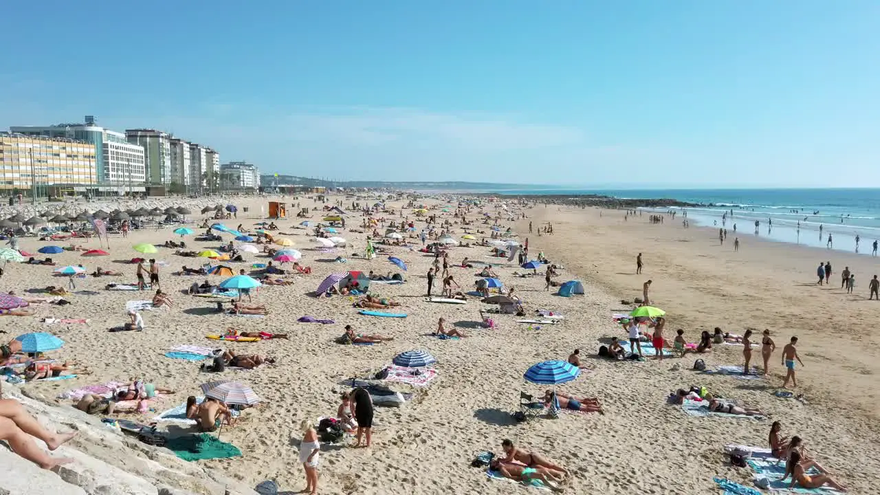 Crowded Praia do Tarquínio-Paraíso beach with Praia do Dragão Vermelho and Praia Nova beaches in the background in Costa da Caparica Portugal