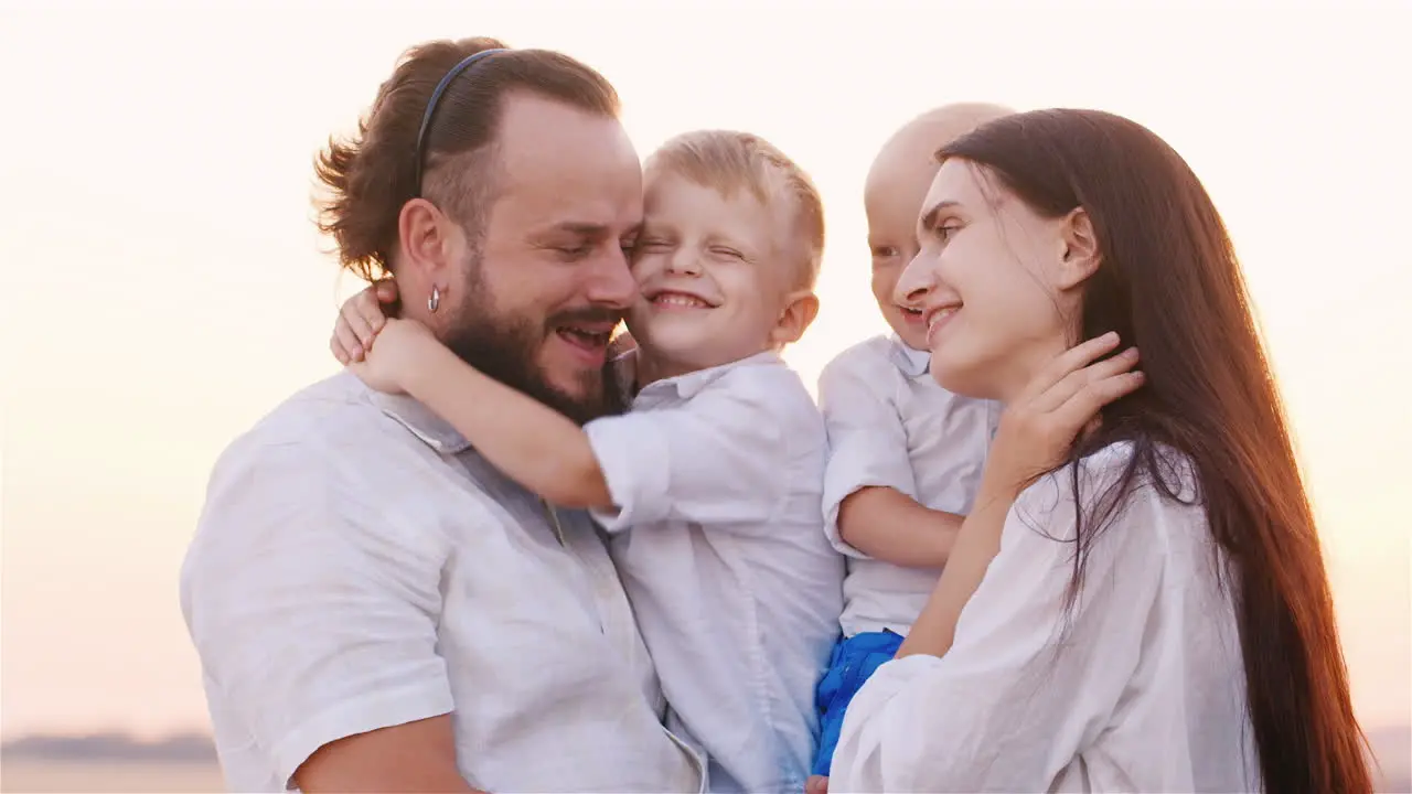 Portrait Of A Young Family With Two Young Sons Smiling At The Camera Hugging Each Other