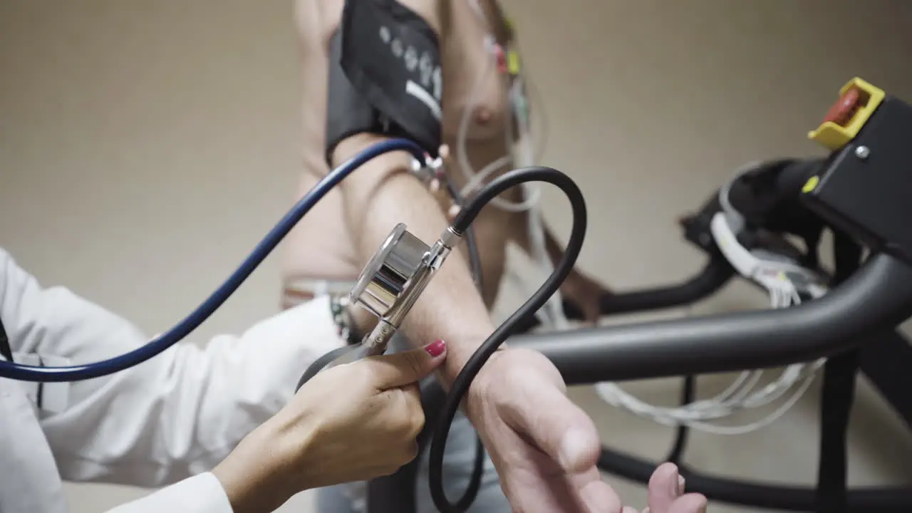 Checking blood pressure levels on a walking athlete on treadmill