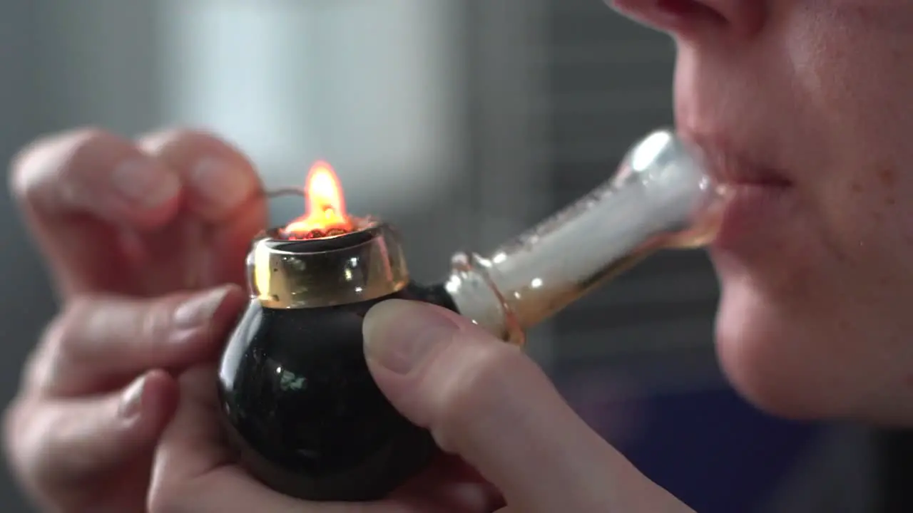 Woman Lighting And Smoking Medical Marijuana Through A Pipe