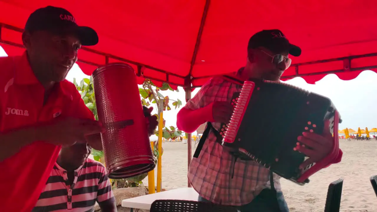 A man is playing the Guacharaca and the accordion