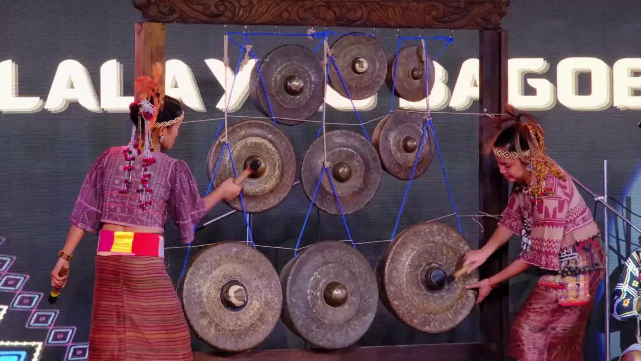 Women in their native costume play music using the Agong instruments