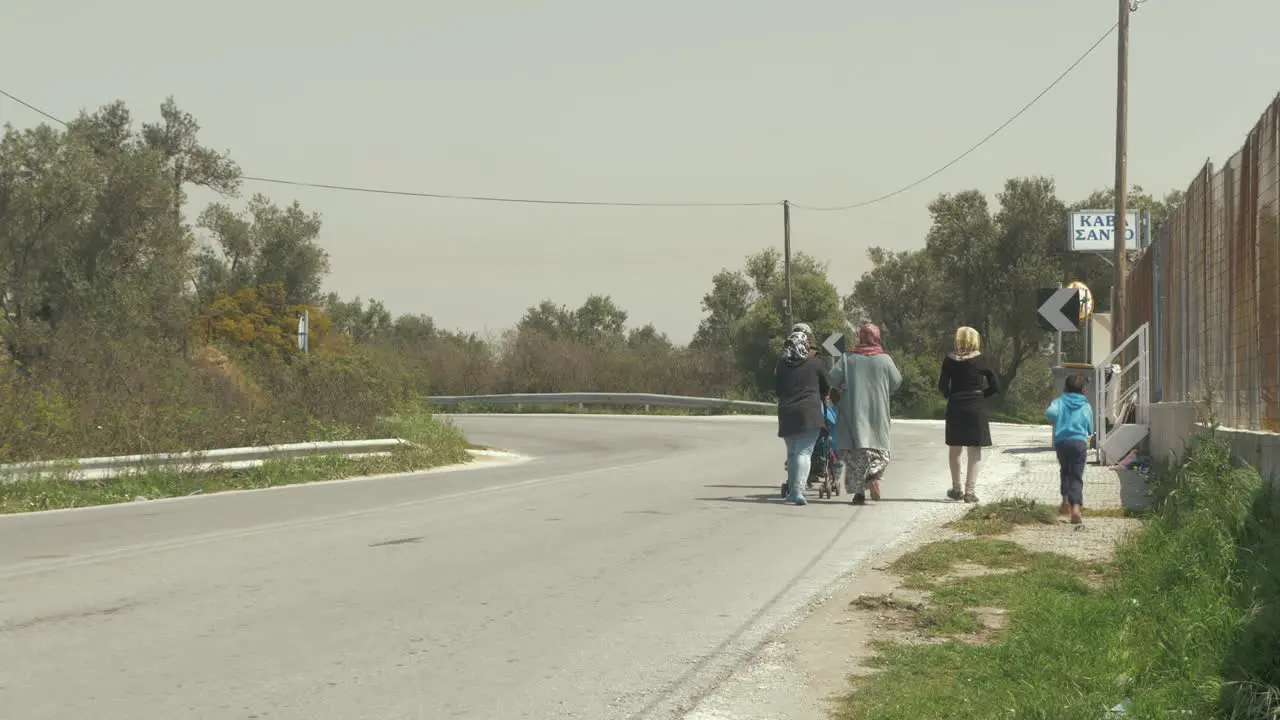 Refugees walk along road in Greece hot Summers day