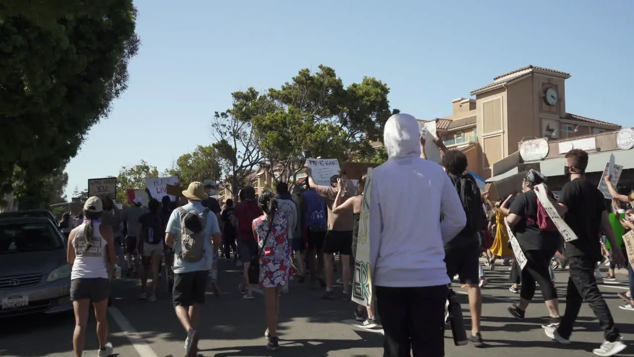 Young hooded male rides skateboard during George Floyd protest