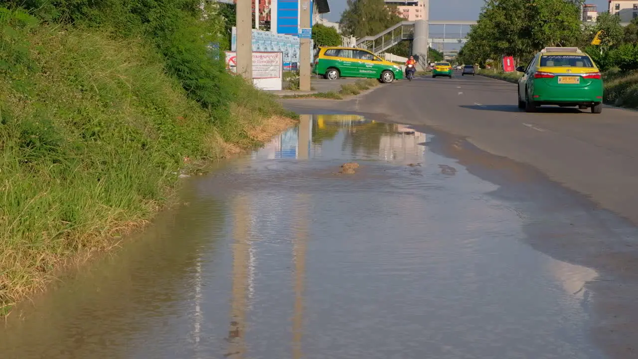 Man Driving Motorcycle Driving On Road With Flood Due To Underground Broken Pipe In Thailand