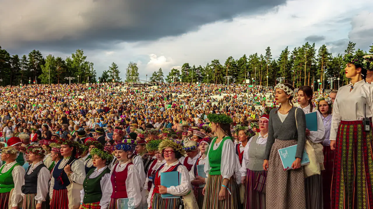 Timelapse of massive moving Crowd gathering at the Latvian Song and Dance Festival with moving clouds during sunset in Riga Latvia