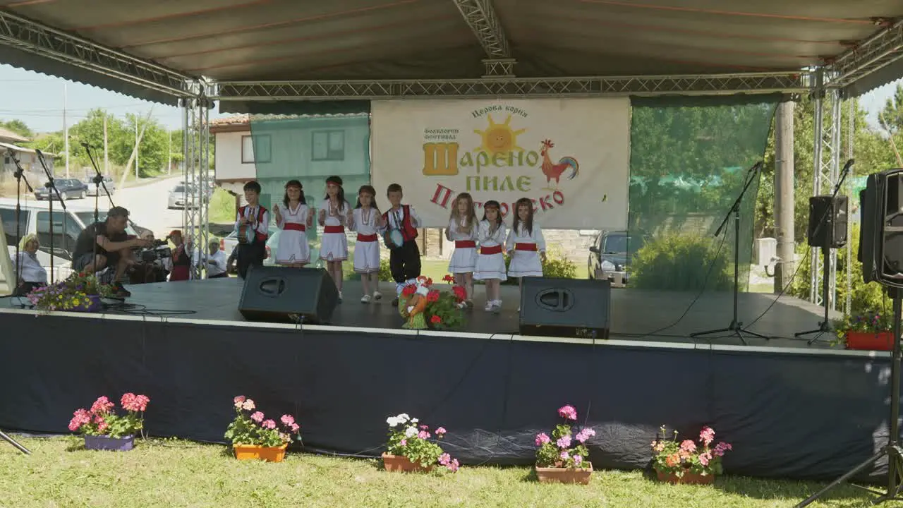 Young children in Bulgarian dress perform on summer festival stage