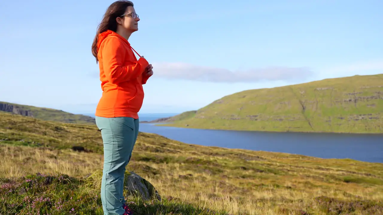 Relaxed woman on a mound admiring the Faroese beauty of Lake Sorvagsvatn