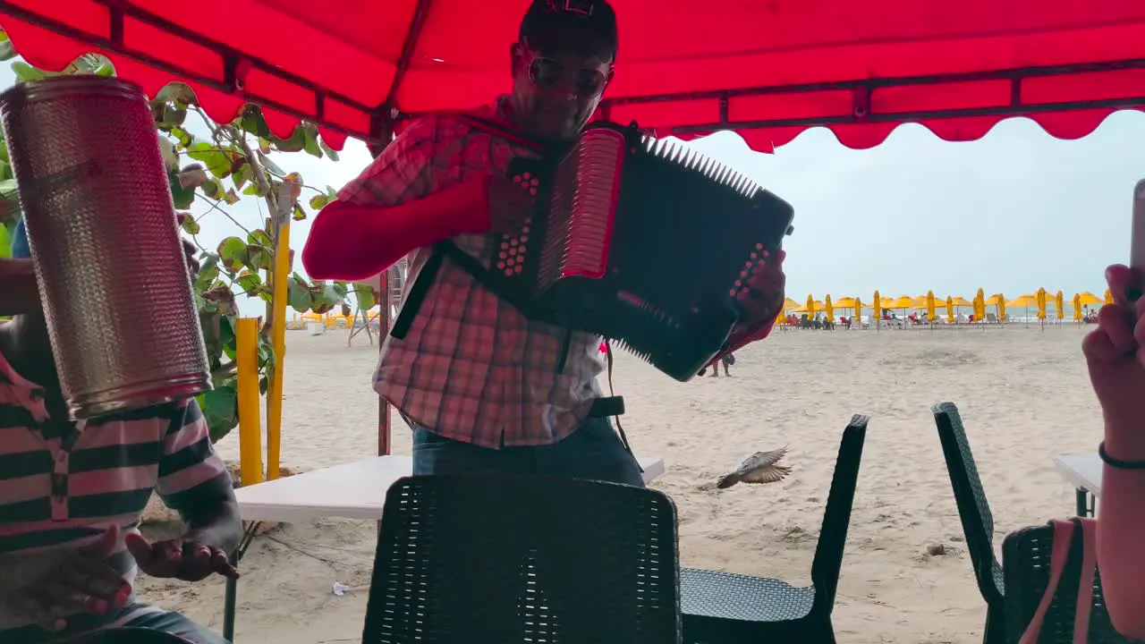 A man plays the accordion next to a man who plays the caja and guacharaca