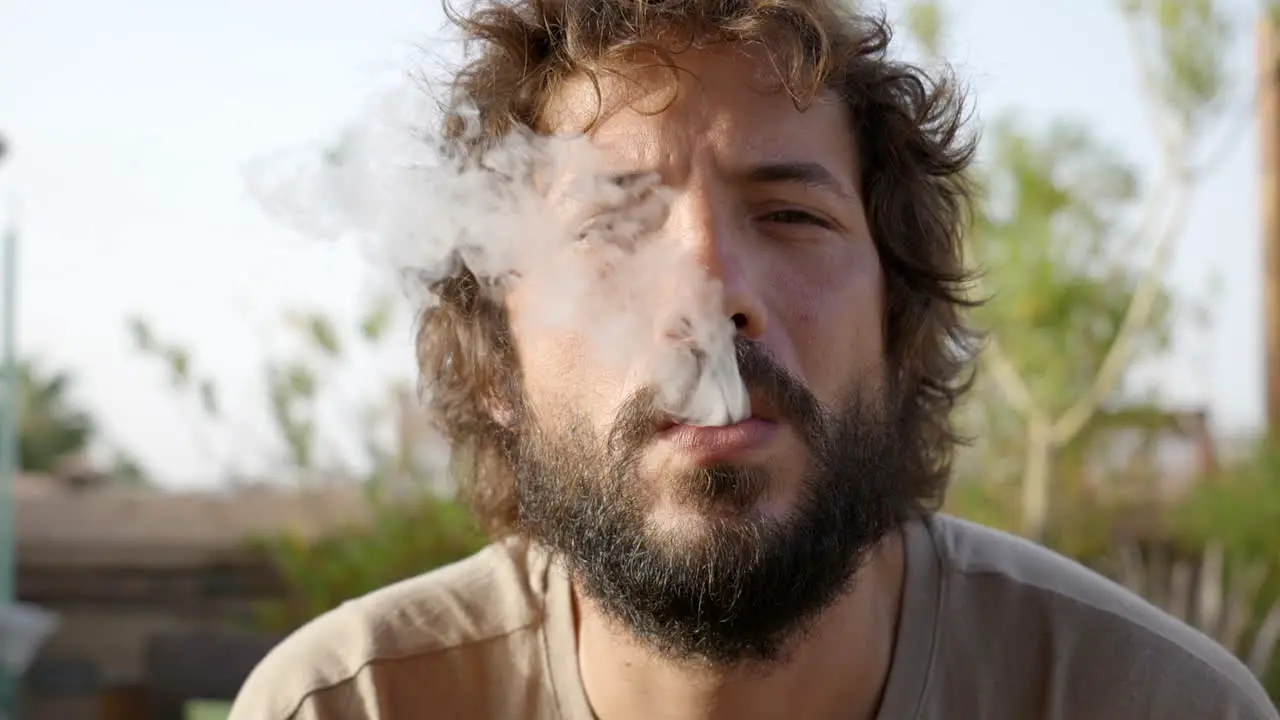 bearded young man enjoying smoking an electronic cigarette