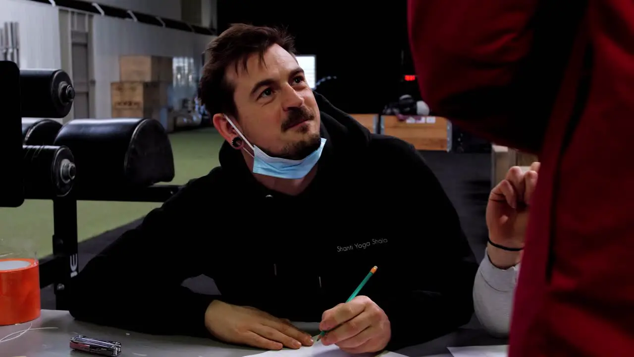 People wearing masks sit around a table diligently recording data