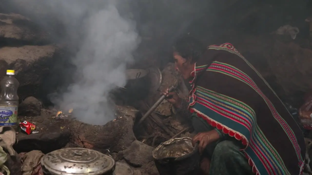 Native Bolivian Grandmother Blows Air in Traditional Stove Prepares for Cooking