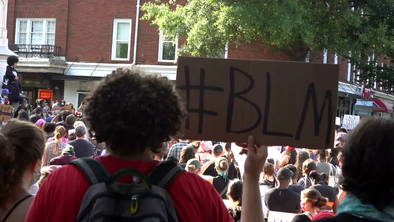 Activist at black lives matter protest holding up a #blm cardboard sign in the city streets