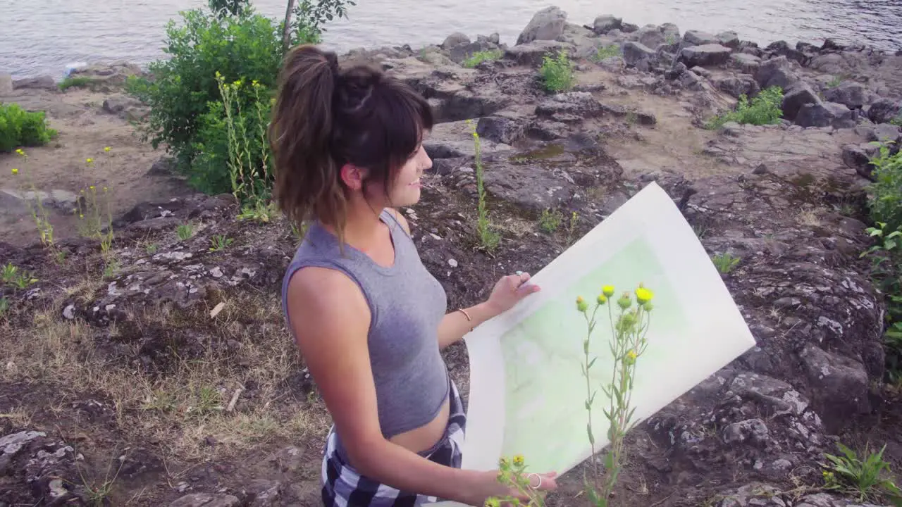 Cute hipster girl opening up a paper map and exploring the park she is in