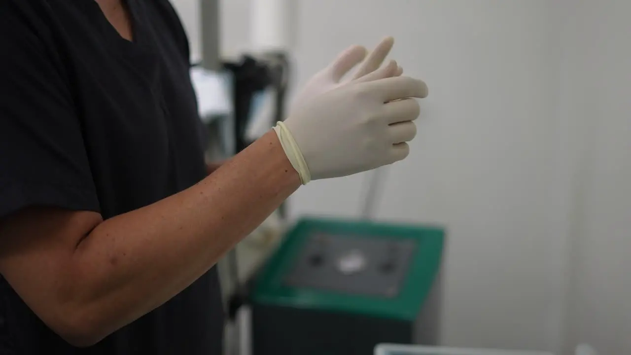 nurse putting gloves on her hands in operating room