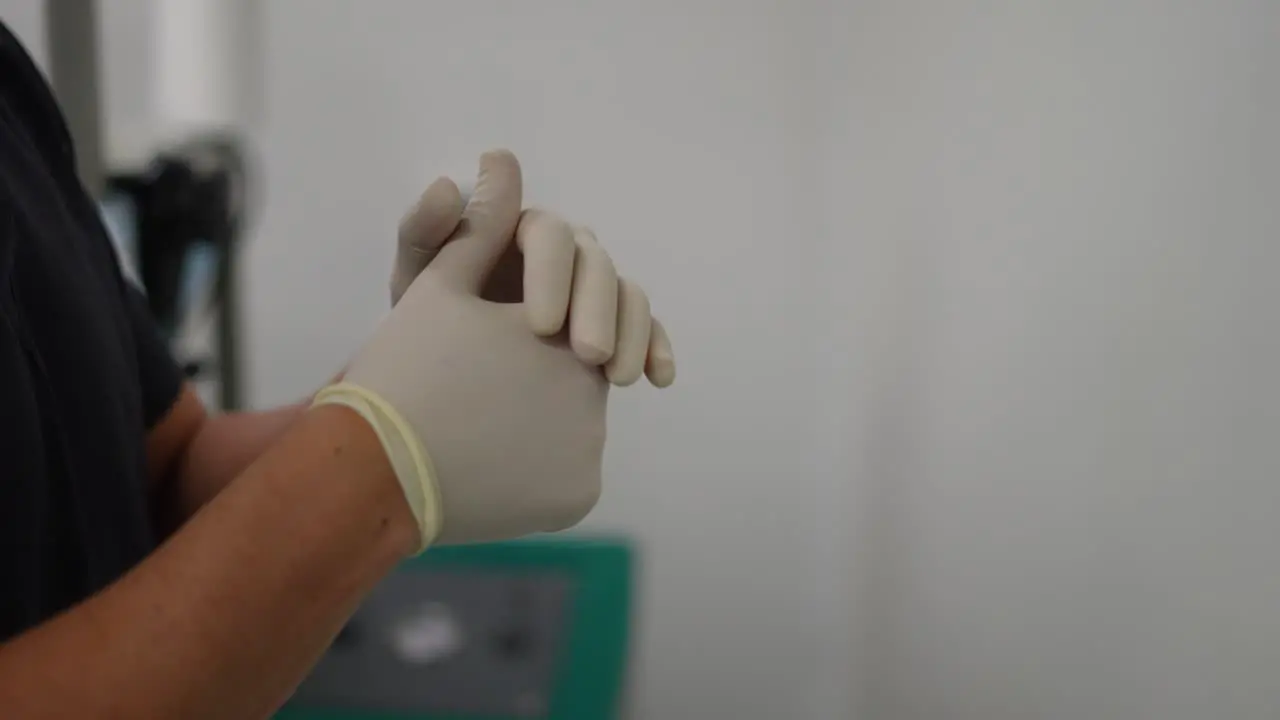 nurse putting gloves on her hands in hospital operating room