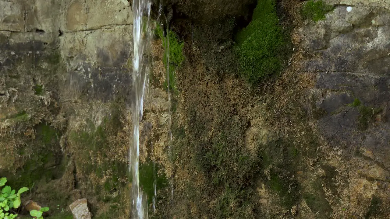 Water fountain falling from carved old stone covered in moss on mountain village of Dardha in Albania