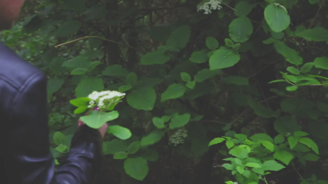 Girl walking on a narrow path in the forest smelling flowers and showing them to the camera slow motion