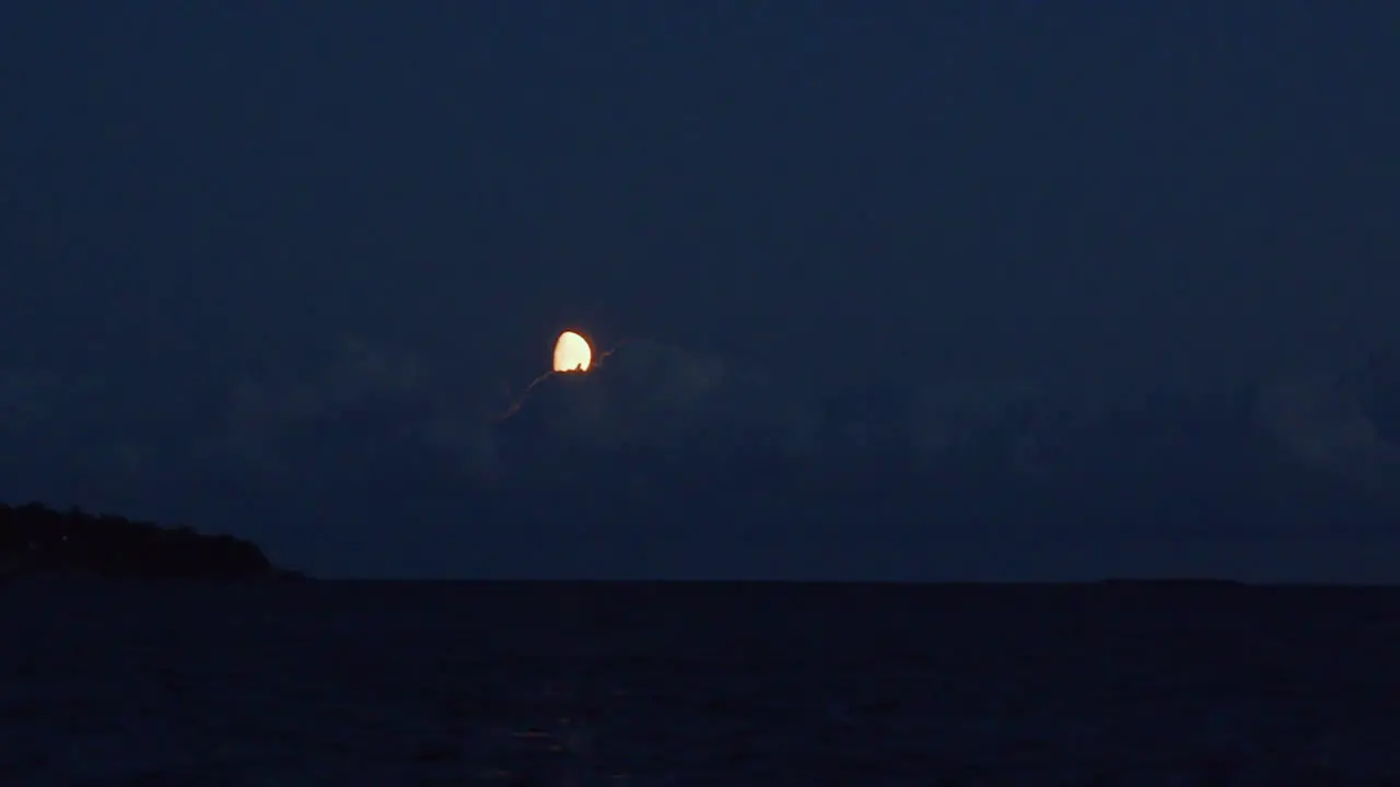 Clouds moving over the moon at night over the sea