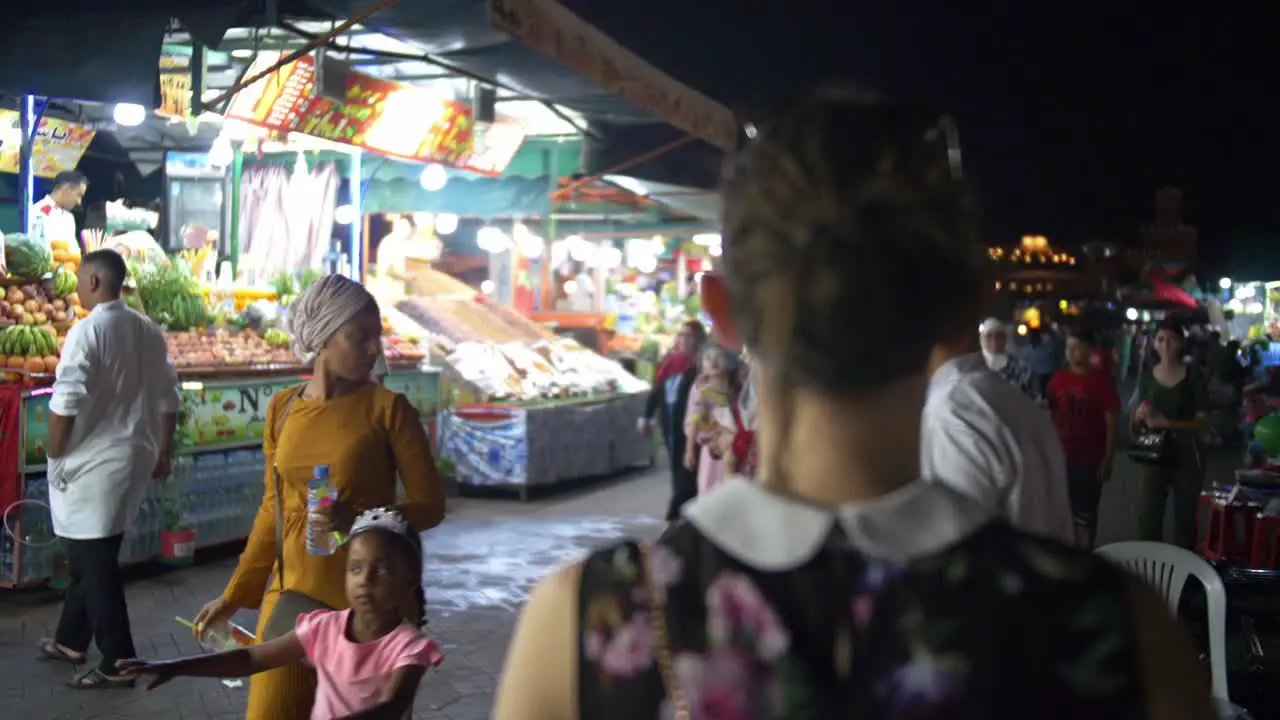 Girl walking through night markets in Marrakesh Morocco exploring the local culture busy crowds with lots of people