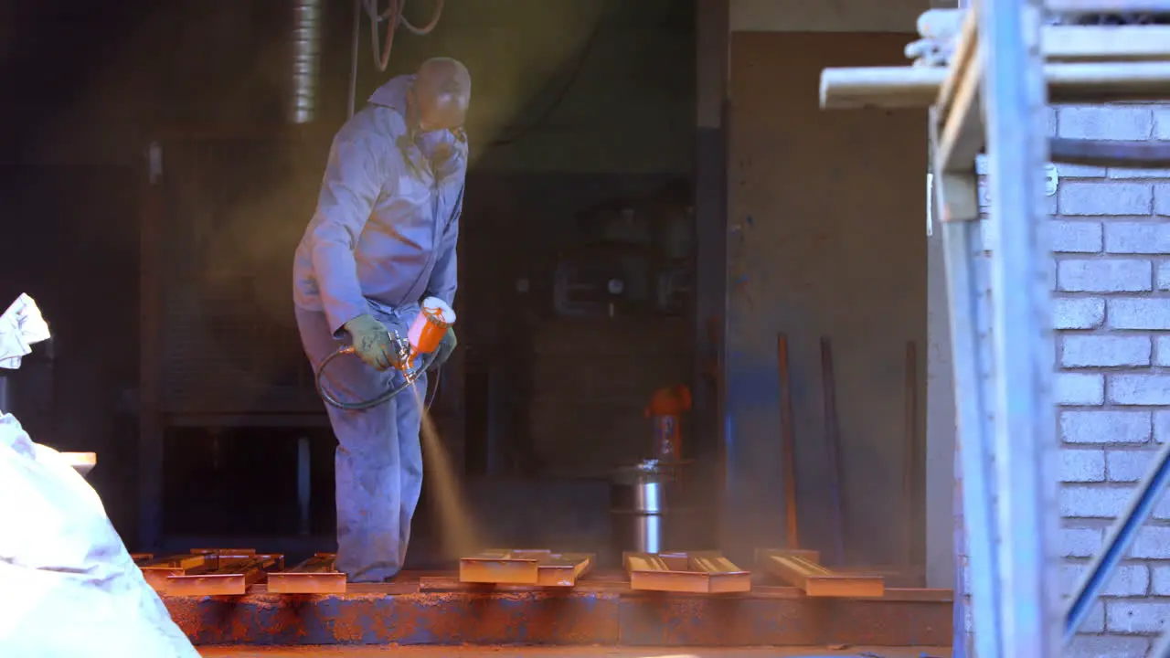 Metalsmith using spray painting machine in workshop 4k